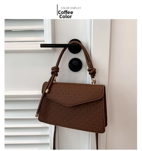 Detail showing the coffee color woven texture and flap design of the crossbody bag