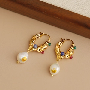 Macro view of vintage earrings with colorful beads and white baroque pearls in gold setting