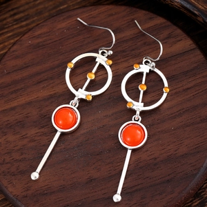 Vintage Ohrhänger mit orangen Edelsteinen und geometrischen Silberringen auf Holzgrund