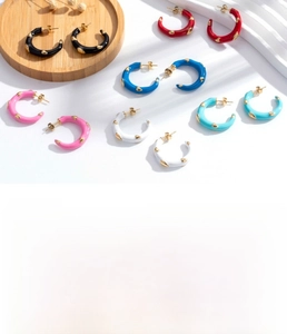 Macro shot of colorful enamel C-shaped titanium steel earrings with 3D gold dot details