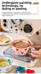 Detail of hand-painted ceramic wave mug with red hearts and a small purple flower cup
