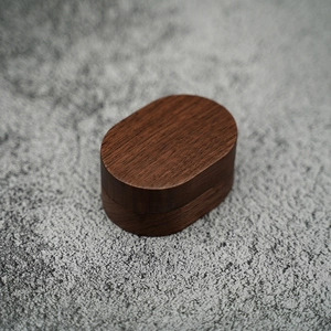 Close-up of oval dark walnut wood jewelry box with natural grain on stone background