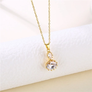 Detail of a gold stainless steel necklace with a round crystal zircon pendant on a white stand