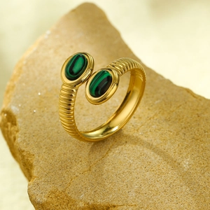 Close-up of a gold stainless steel ring featuring green malachite stones on a rock