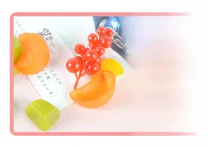 Macro shot of realistic PVC orange slices and red berry models for cake decoration