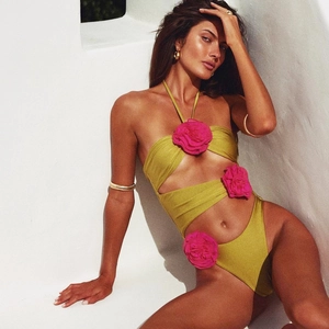 Detail eines grünen Badeanzugs mit 3D-Blumenakzenten und modischen Cut-outs am Bauch