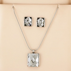 Detailed shot of square grey crystal jewelry set with silver snake chain in a beige box
