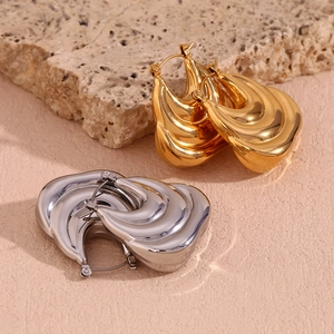 Three-layer wave hollow earrings in gold and silver finish on natural rock