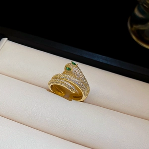 Detailed view of snake-shaped gold ring with white zircon pavé and green gemstone eyes