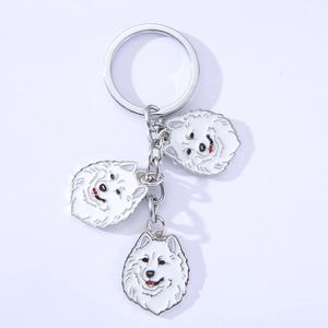 Detail of three white enamel Samoyed dog charms on a polished metal keychain