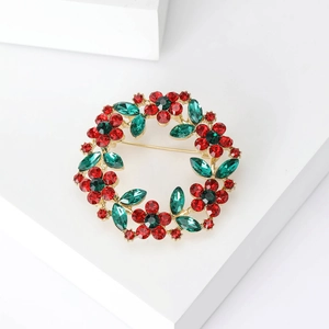 Detailed view of rhinestone floral wreath brooch with red crystals and gold finish