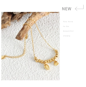 Macro detail of 18k gold lotus pod and tulip charms on a titanium steel beaded anklet