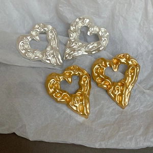 Macro detail of irregular lava texture on heart-shaped gold and silver metallic earrings