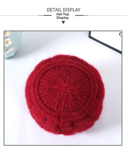 Detail view of the plush knitted top of a warm winter hat with golden thread accents