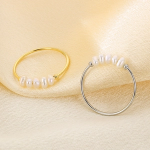 Dettaglio di anelli con perle color oro e argento su uno sfondo di seta lussuoso color champagne