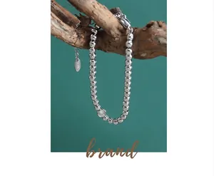 Detailed close-up of beaded silver bracelet with zircon pendant on artistic wood branch