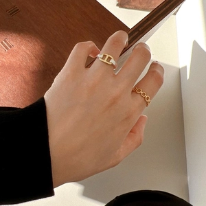 Close-up of stacked gold twist rings with crystal-inlaid link design on model's hand