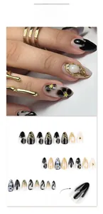 Detail of JP3788 almond press-on nails with 3D black floral design and gold foil textures