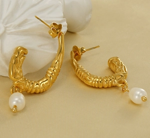 Vue détaillée de boucles d'oreilles dorées en U avec texture et perles blanches pendantes