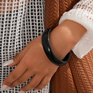 Macro view of polished dark resin round bangle with elegant glossy finish and textures