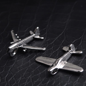 Detailed macro of silver-tone jet and propeller plane pendants on black leather