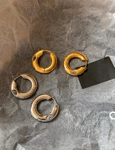 Detailed macro view of gold and silver chunky hoop earrings with marquise-cut zircon stones