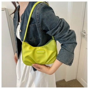 Detail of neon green pleated crescent bag worn over shoulder with sleek texture