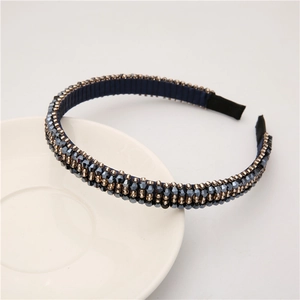 Close-up of baroque style narrow headband featuring navy blue crystals and gold beads