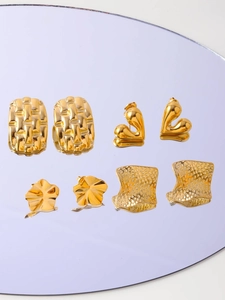 Detail of four pairs of vintage gold irregular geometric earrings on a purple mirror