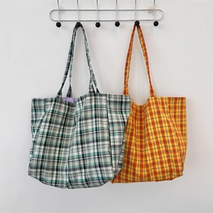 Vue détaillée de deux grands sacs cabas en toile à carreaux verts et orange suspendus