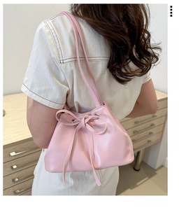 Dettaglio della borsa a secchiello in pelle PU rosa con coulisse, fiocco e tracolla sottile