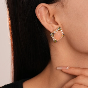 Makroaufnahme von Vintage-Ohrringen mit rosa Kristallen und Perlen am Model getragen