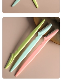 Detail of colorful eyebrow razors with safety mesh blades on a neutral tabletop