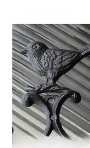 Close-up of vintage cast iron bird hook with rustic texture and industrial finish