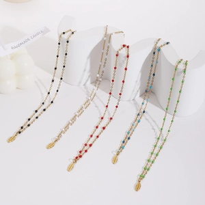 Detailed view of layered beaded necklaces with gold leaf pendants in five vibrant colors