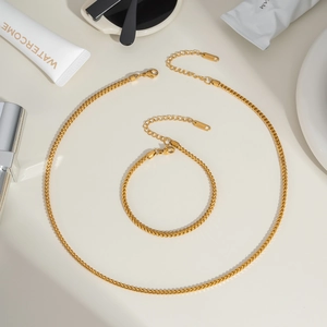 Flat lay of gold stainless steel wheat chain necklace and bracelet set with lobster clasp