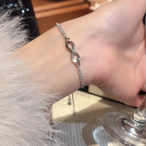 Close-up of silver infinity bracelet with zircon stones on a woman's wrist with soft textures
