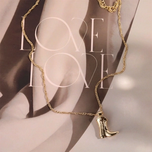Detail of a gold-plated cowboy boot pendant on a water wave chain necklace