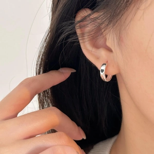 Close-up of 925 silver hoop earring with black heart charm worn on a model's ear