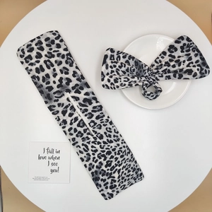 Detail of grey leopard print hair bun maker and matching bow headband on a white plate