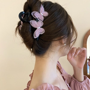 Detailed view of an elegant lace butterfly hair claw with pearls on a model's hair