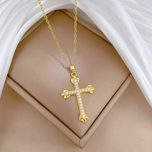 Close-up of golden titanium steel cross necklace with zircon stones in a jewelry box