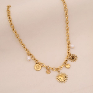 Macro detail of gold-plated charms featuring pearls, sun motifs and beetle coins