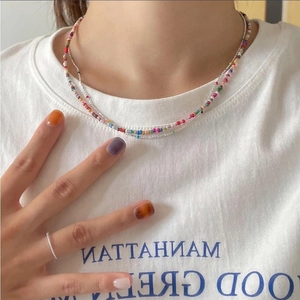 Detail of layered jewelry featuring colorful handcrafted beads and a fine silver chain