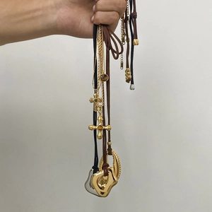 Hand holding assorted tiger eye stone and 18K gold plated stainless steel necklaces