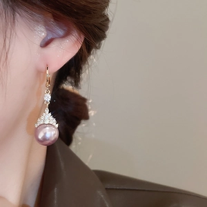 Détail de mannequin portant des boucles d'oreilles dorées avec perles violettes
