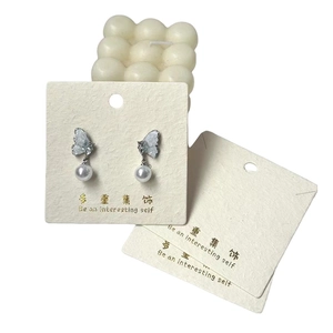 Elegant butterfly drop earrings with white pearls on a display card for jewelry store