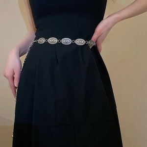 Detail of silver oval carved metal chain belt with adjustable links on model