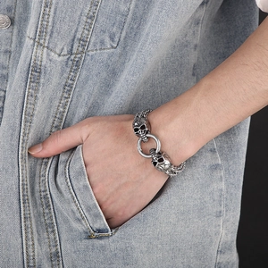 Detail of a vintage silver skull bracelet worn on a wrist against blue denim background