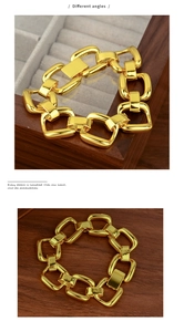 Detail view of bold gold chain link bracelet with polished mirror finish and square clasp
